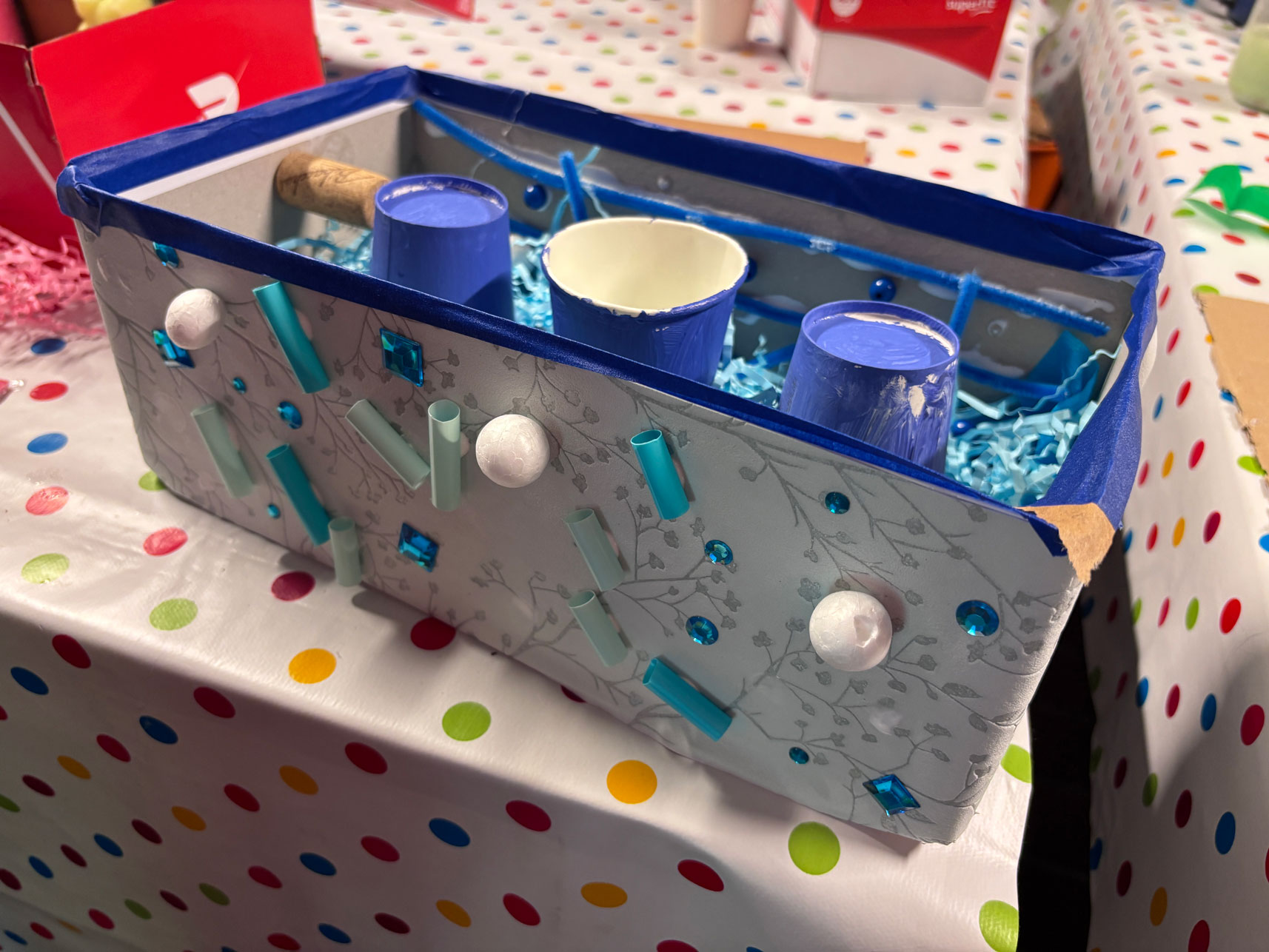 Dekorierte Box mit blauen Pappbechern und blauen Dekoelementen außen