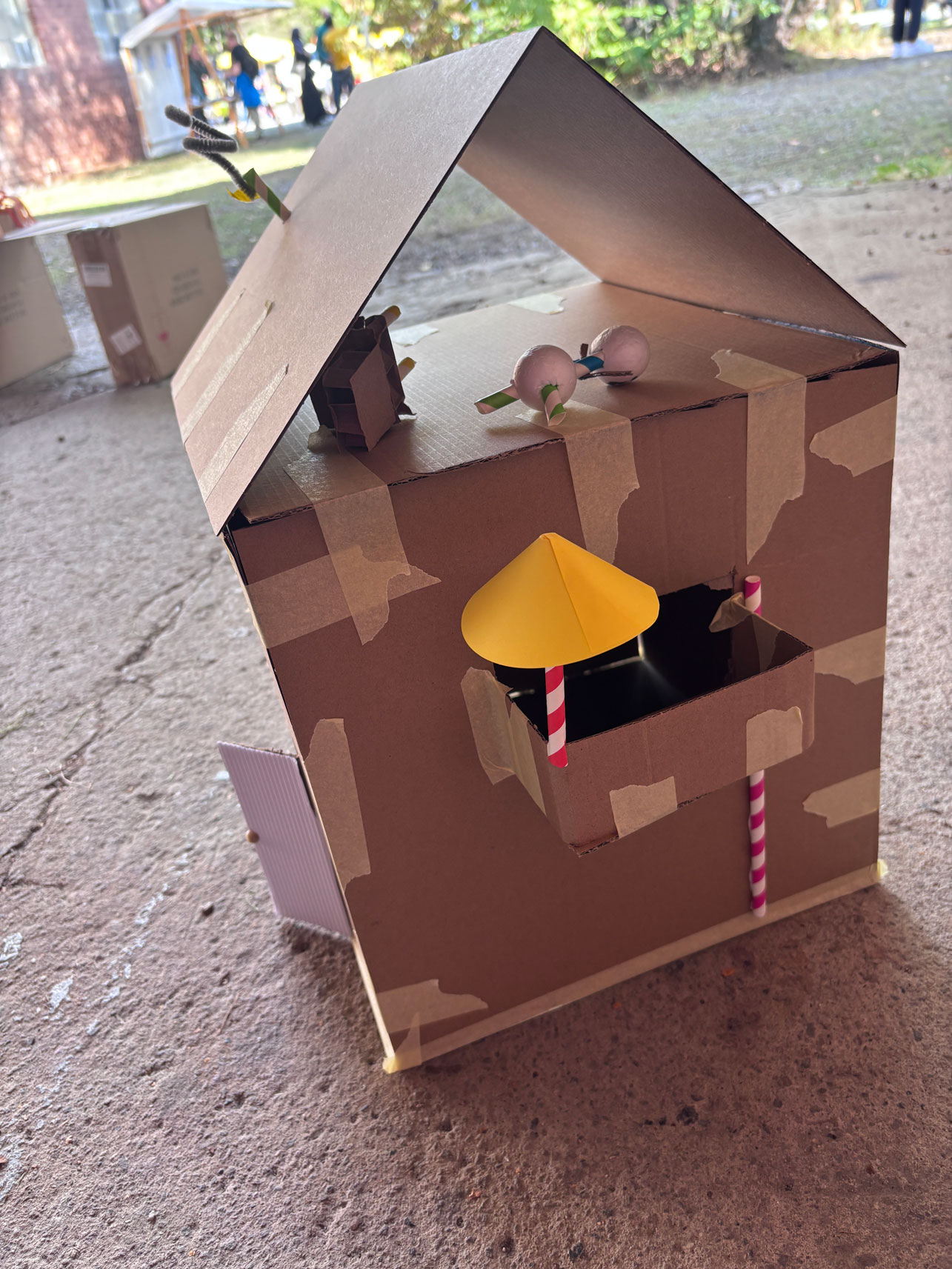Haus aus Pappe mit Balkon und Sonnenschirm darauf